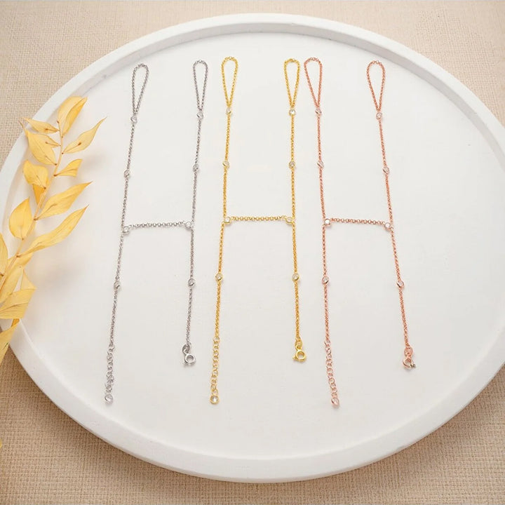 Three gold-plated handchains on a white plate with decorative leaves.
