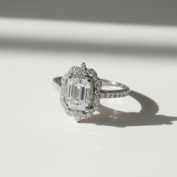 Diamond ring with a central emerald-cut gemstone on a light background
