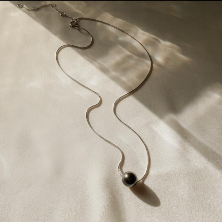 Necklace with a black pendant on a beige fabric background