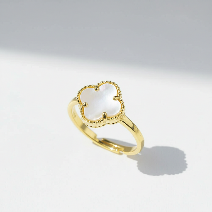 Gold ring with a clover-shaped center on a light gray background