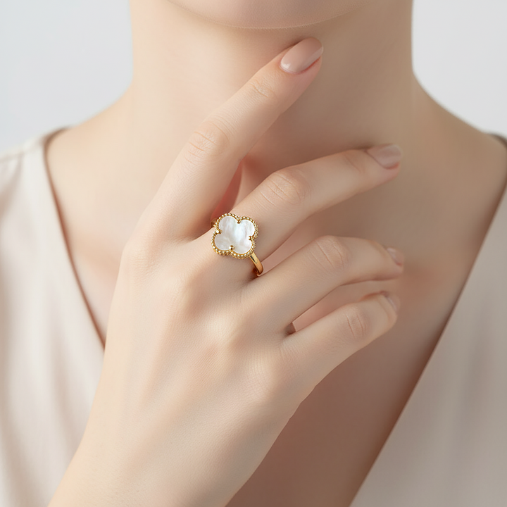 Gold ring with a central gemstone on a hand against a neutral background
