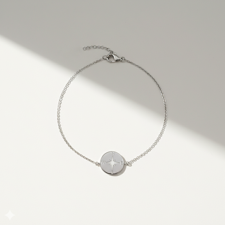 Silver bracelet with a compass charm on a light gray background