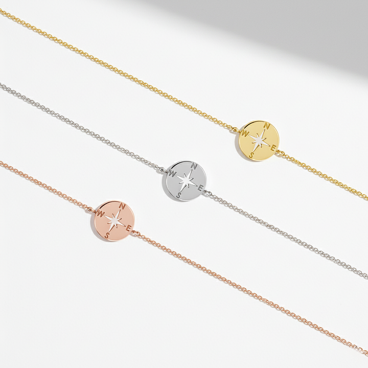 Three gold, silver, and rose gold bracelets with compass designs on a light gray background.