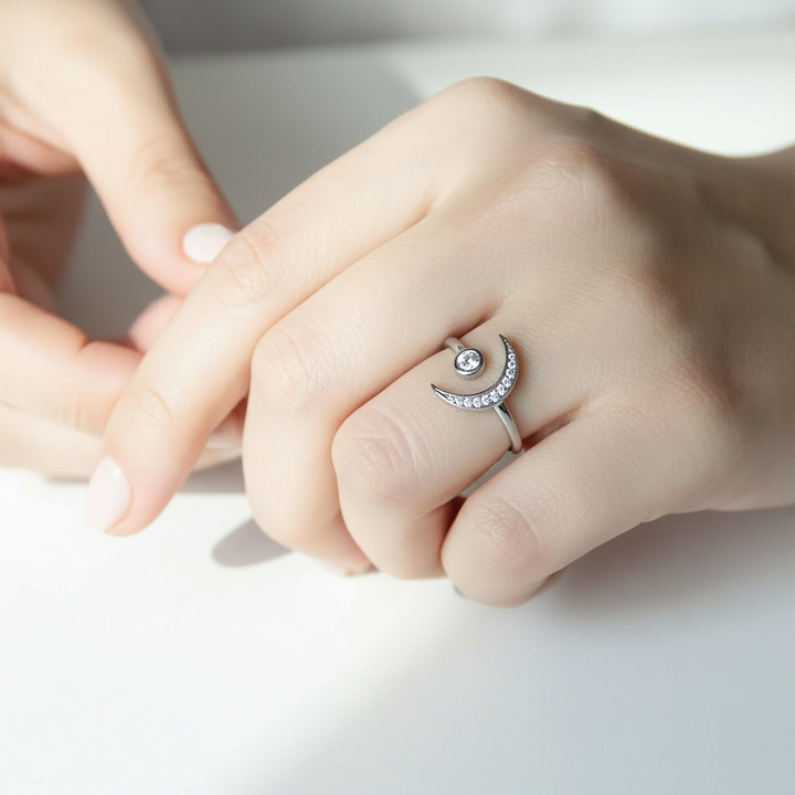 Close-up of a hand wearing a silver ring with a diamond on a light background