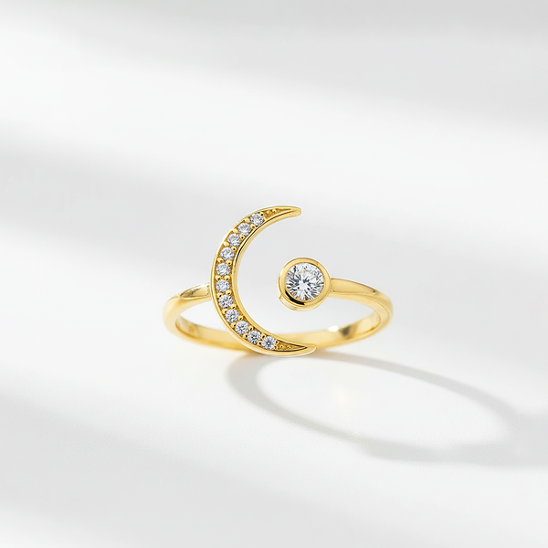 Gold ring with a crescent moon design and small gemstone on a light gray background