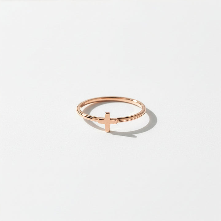 Rose gold ring with a cross design on a light gray background