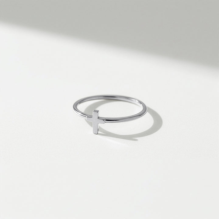 Dainty cross ring in sterling silver on a light gray background