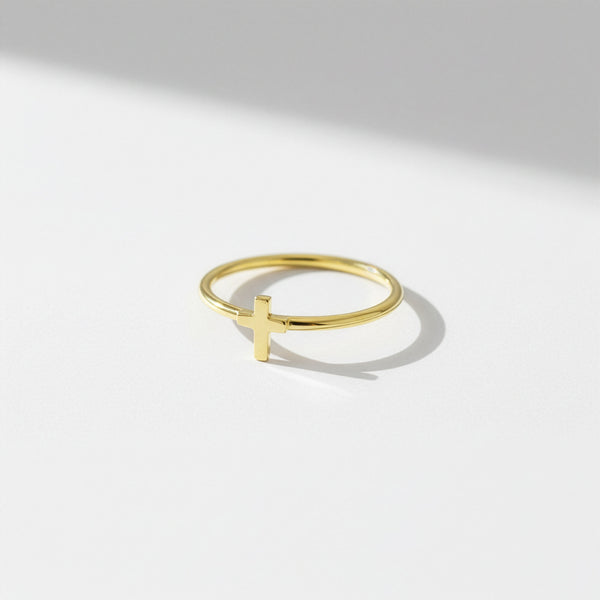 Gold ring with a cross design on a light gray background