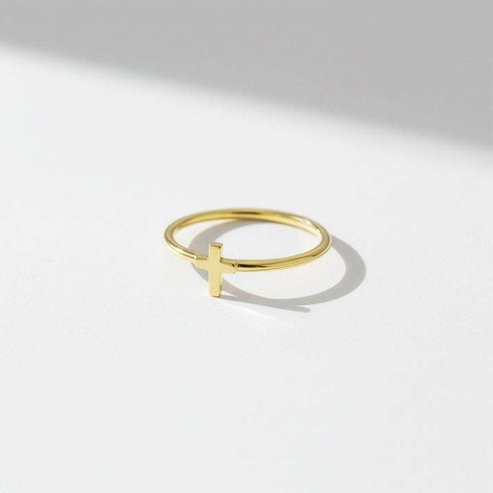 Gold ring with a cross design on a light gray background