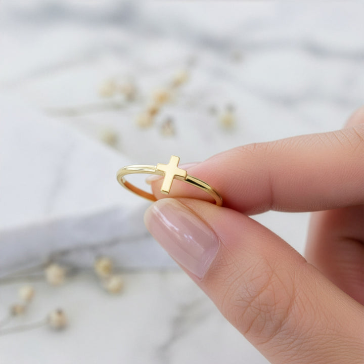 Gold cross ring being held on a blurred background