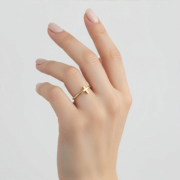 Gold ring on a finger against a plain background
