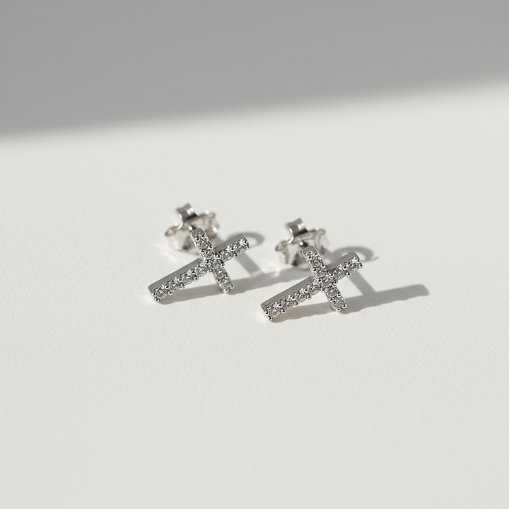 Silver earrings with cross design on a light gray background