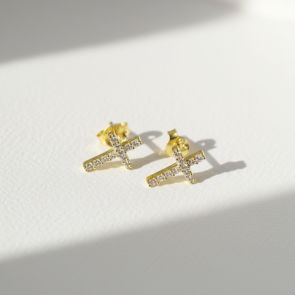 Gold cross earrings with small diamonds on a light background