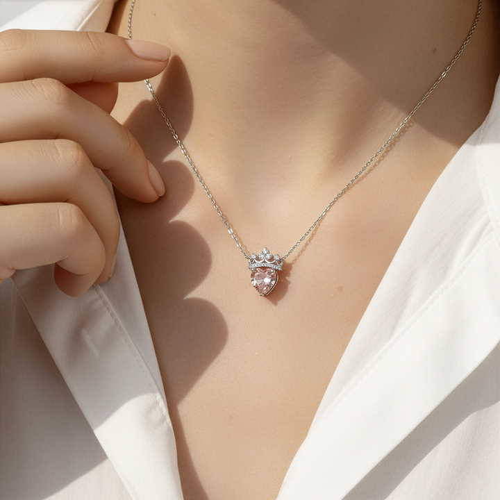 Necklace with a heart-shaped pink gemstone pendant worn by a person in a white shirt.