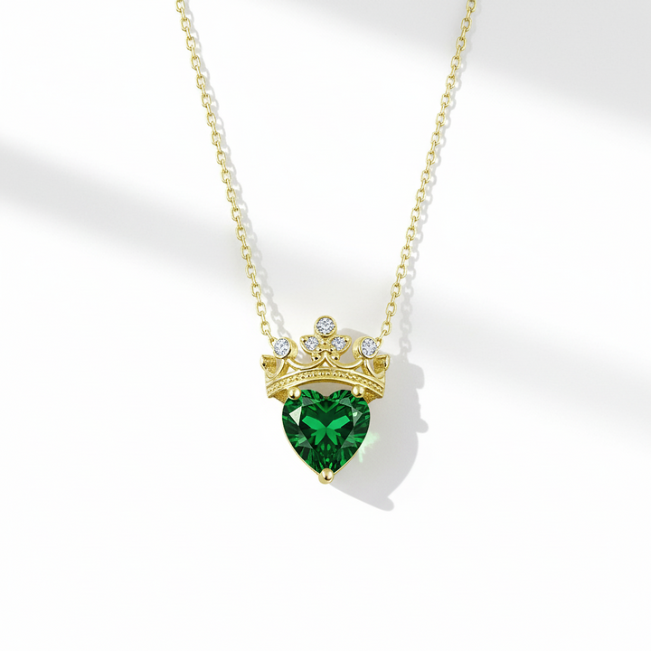 Gold necklace with a green heart-shaped gemstone pendant on a white background