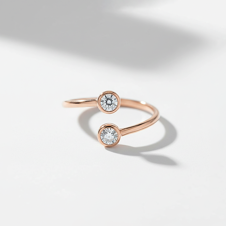 Rose gold ring with two diamond stones on a light gray background