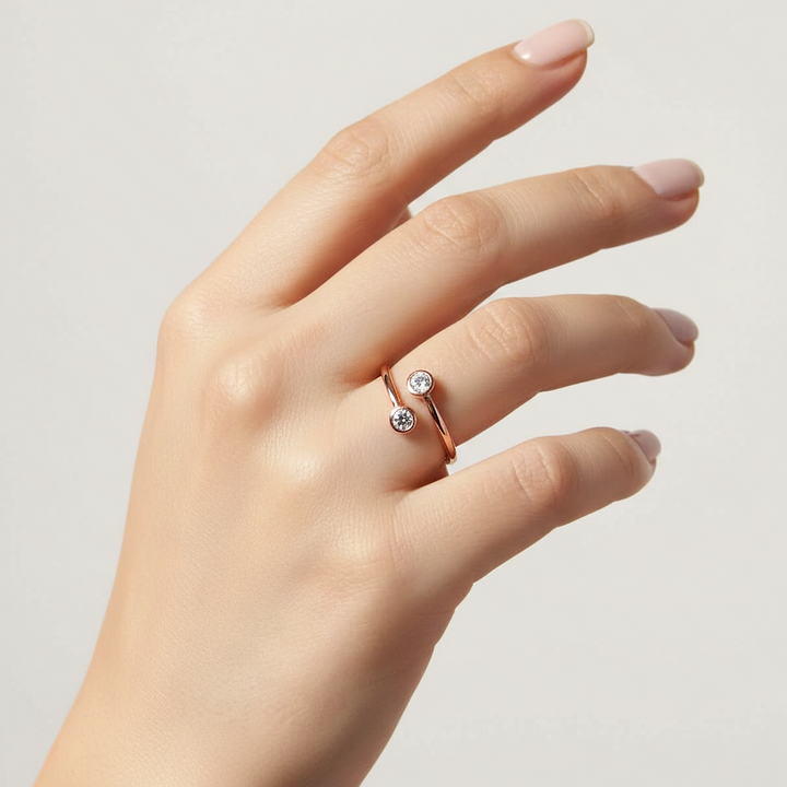 Hand wearing a rose gold ring with two small diamonds on a light background