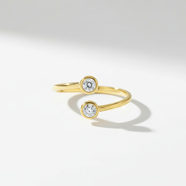 Gold ring with two diamond stones on a light gray background