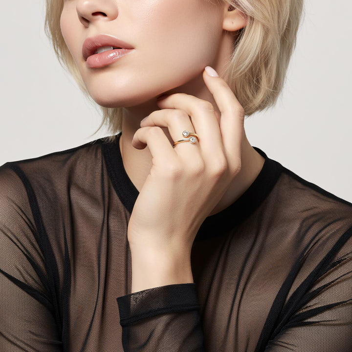Close-up of a woman wearing a gold ring with a diamond on a neutral background