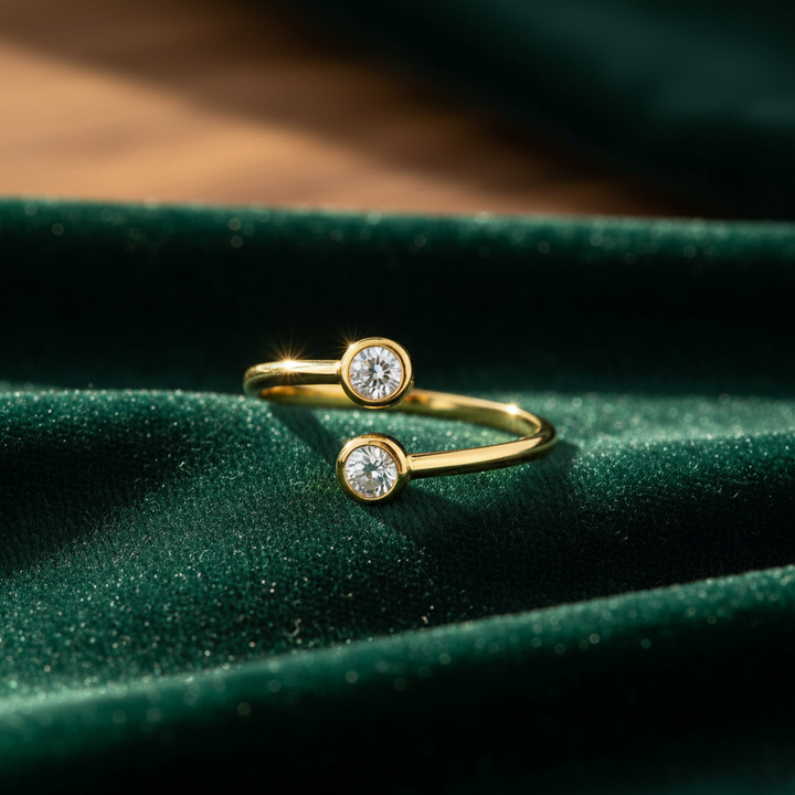 Gold ring with two diamonds on a green fabric background