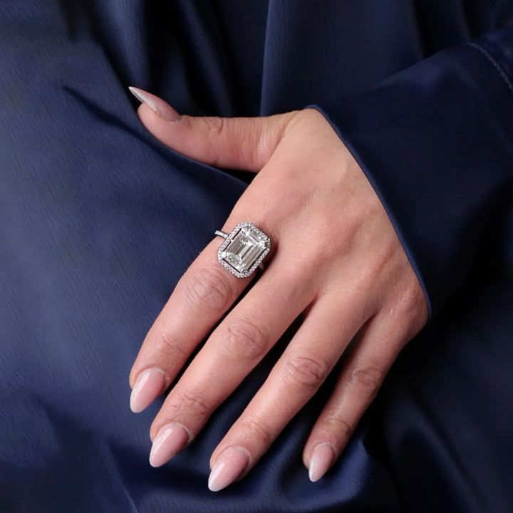 Hand wearing a diamond ring on a dark blue fabric background