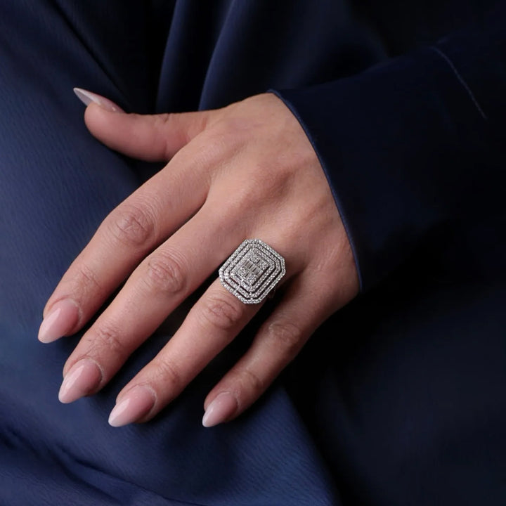 Hand wearing a diamond ring on a dark fabric background