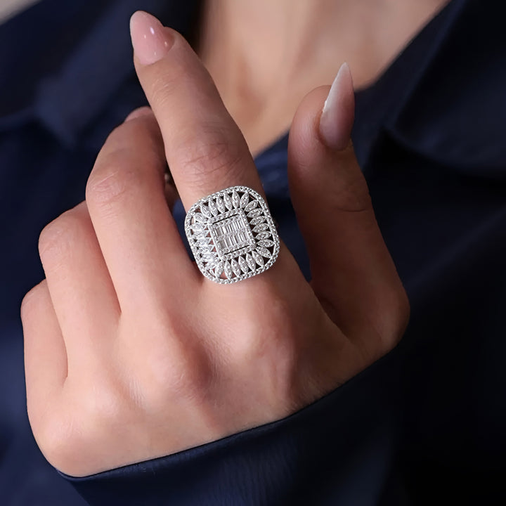 Silver ring with intricate design on a person's finger against a dark background