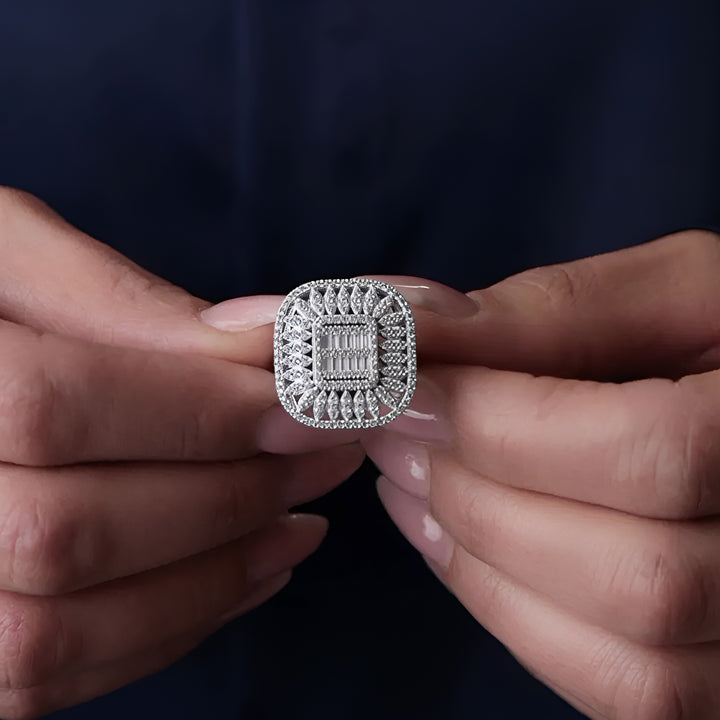 Close-up of a person holding a diamond ring between their fingers against a dark background