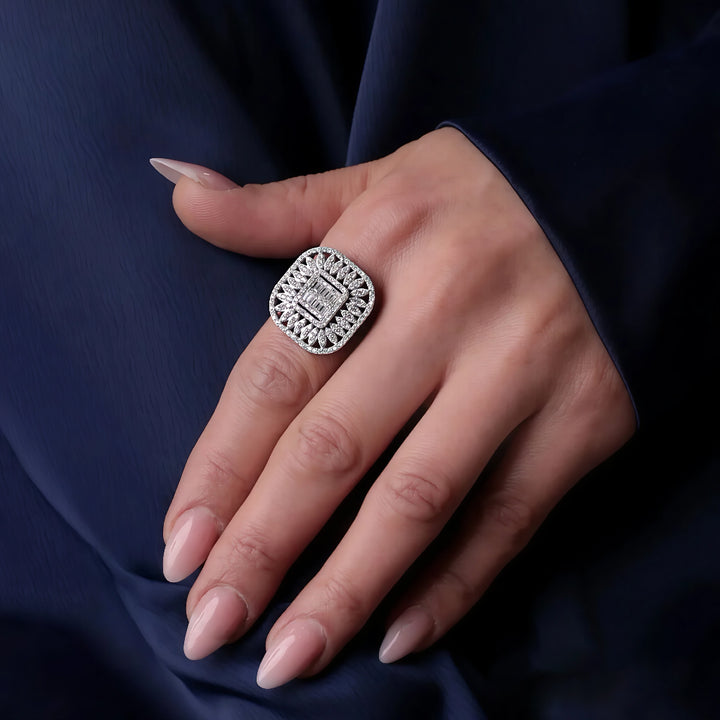 Silver ring with gemstones on a hand against a dark blue fabric background