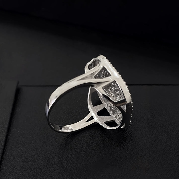 Silver ring with black gemstones on a black background