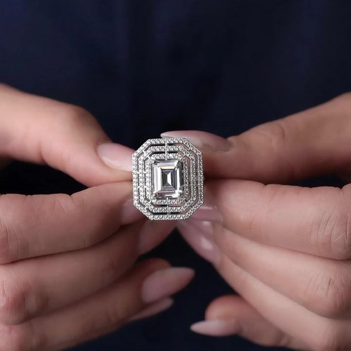 Diamond ring held between two hands against a dark background