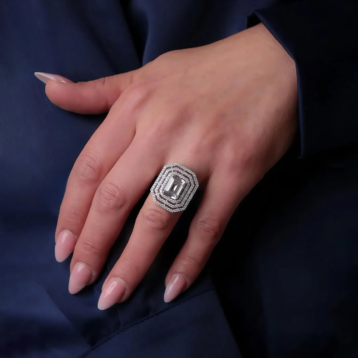 Hand wearing a diamond ring on a dark blue fabric background
