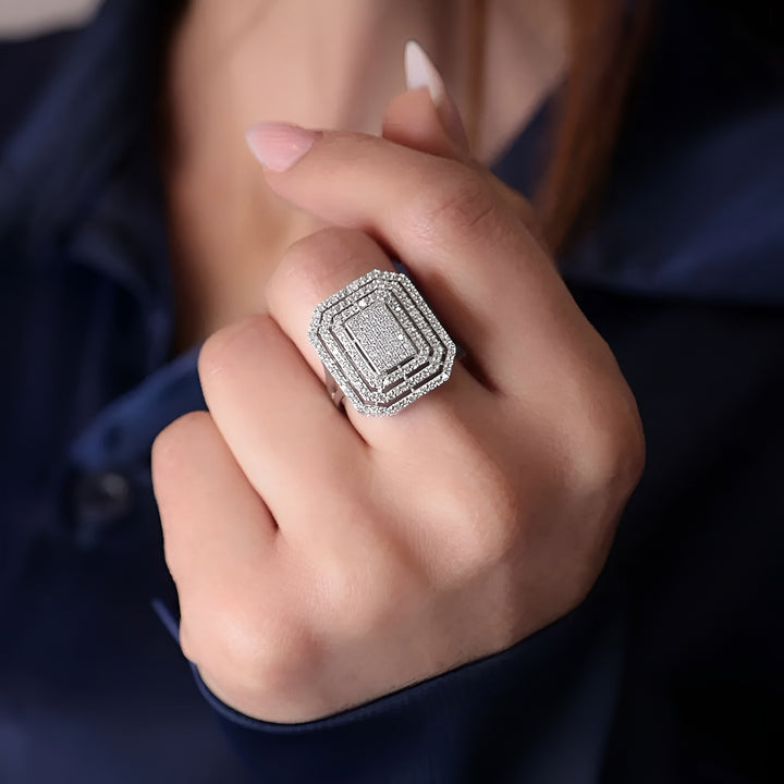 Close-up of a hand wearing a silver ring with gemstones against a dark background