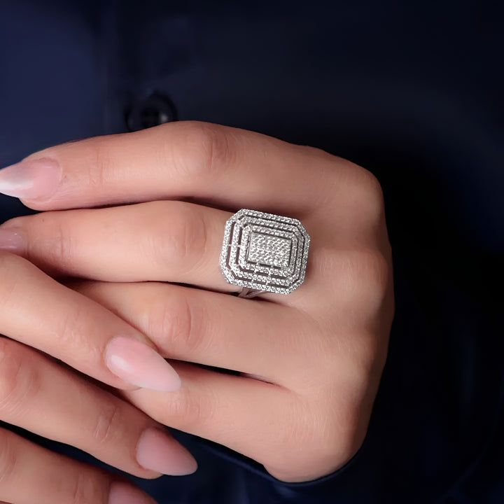 Silver ring with gemstones on a hand against a dark background