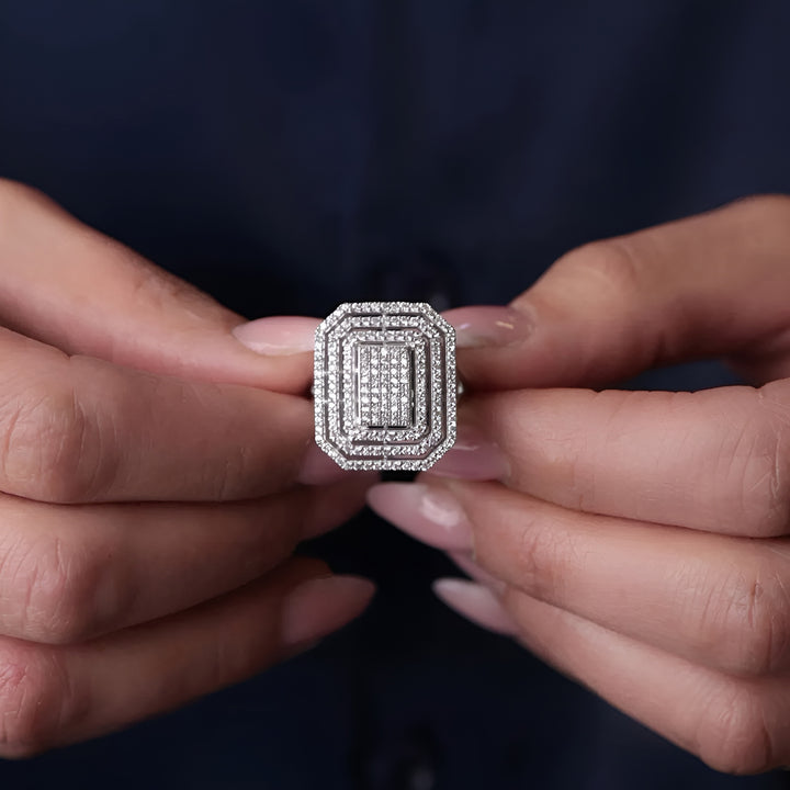 Diamond ring held between two fingers against a dark background