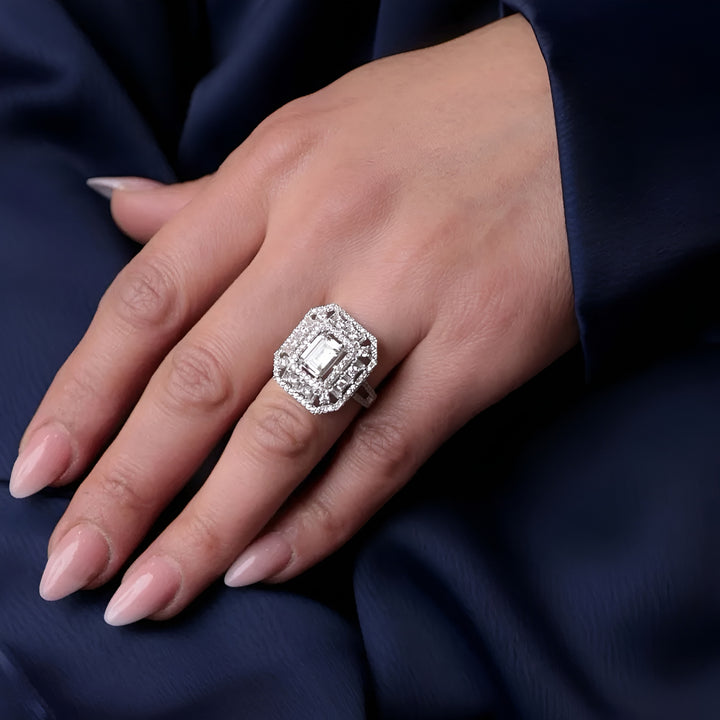 Silver ring with a large diamond on a hand against a dark blue fabric background