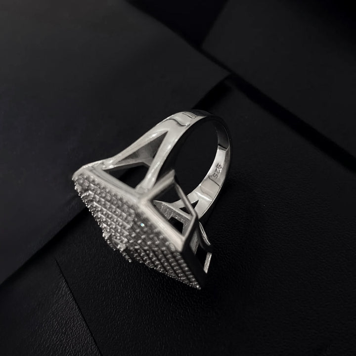 Silver ring with a textured design on a black background