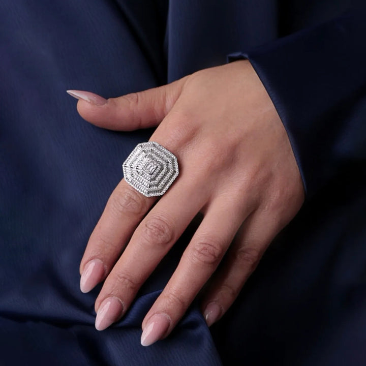 Silver ring on a hand against a dark blue fabric background