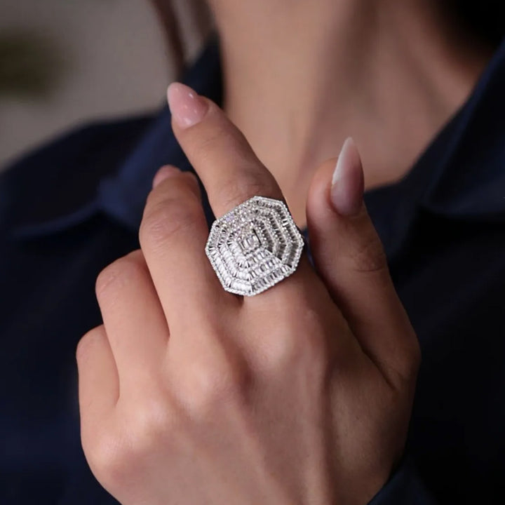 Close-up of a hand wearing a decorative silver ring with a dark background