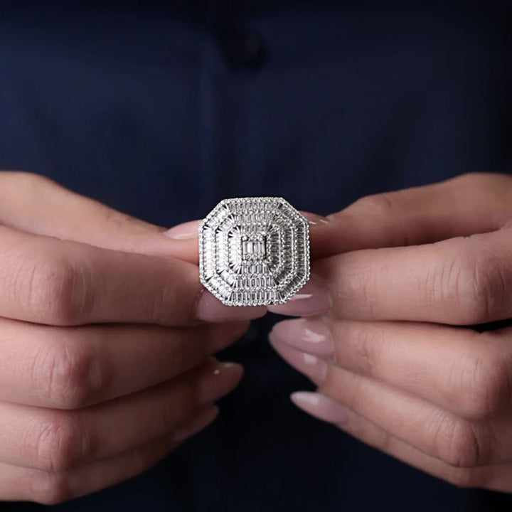 Close-up of a person holding a diamond ring between their fingers against a dark background