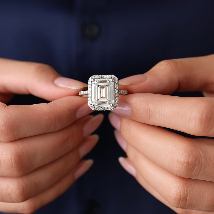 Diamond ring held between two hands against a dark background