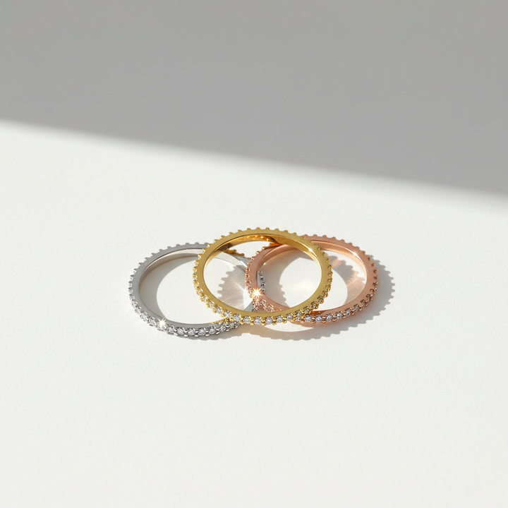 Three gold rings of different widths on a light gray background
