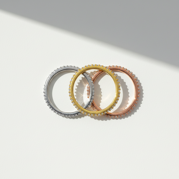 Three rings in silver, gold, and rose gold on a light gray background