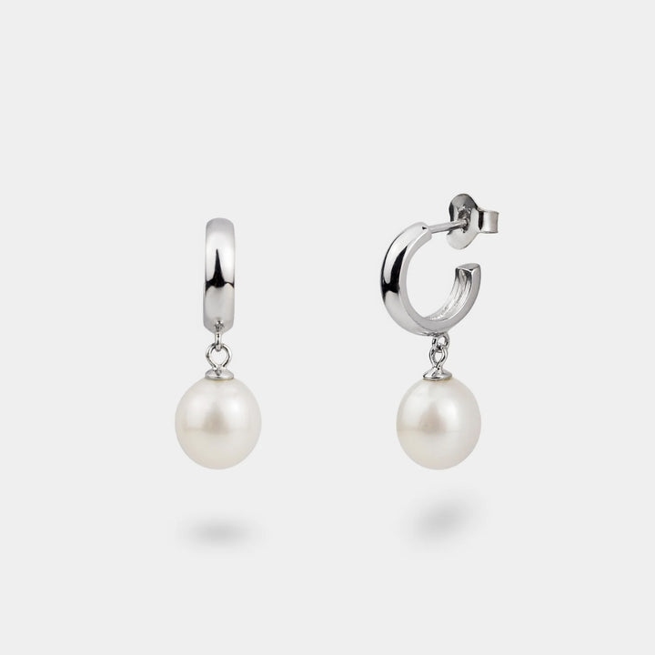 Pair of silver hoop earrings with pearl drops on a white background