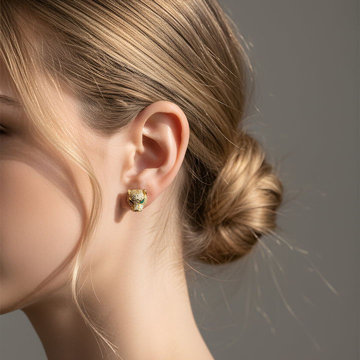 Close-up of a person wearing a gold panther earring with green eyes