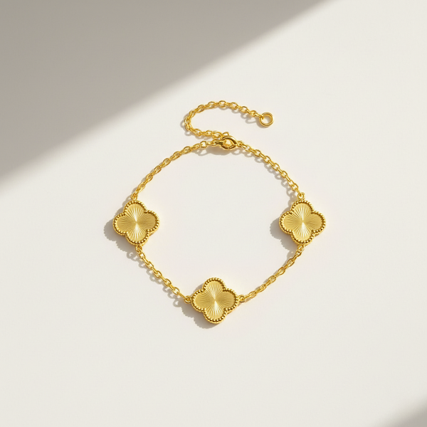 Gold bracelet with clover-shaped charms on a light background