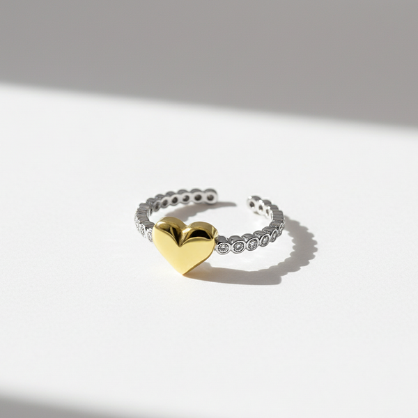 Gold heart-shaped ring on a silver band against a light background
