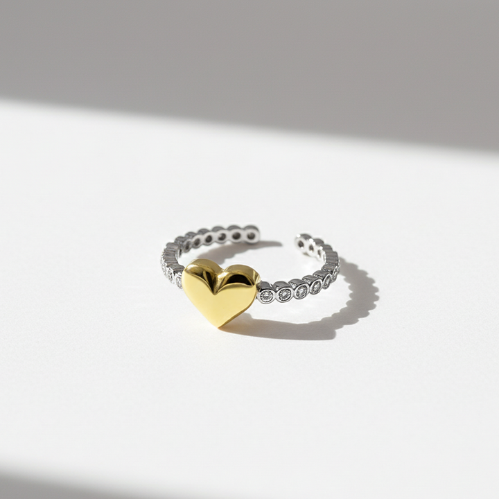 Gold heart-shaped ring on a silver band against a light background