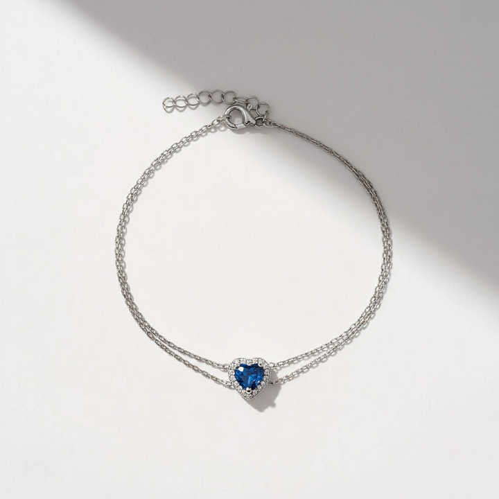Silver bracelet with a blue heart-shaped gemstone on a light background