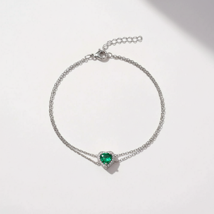 Silver bracelet with a heart-shaped green gemstone on a white background